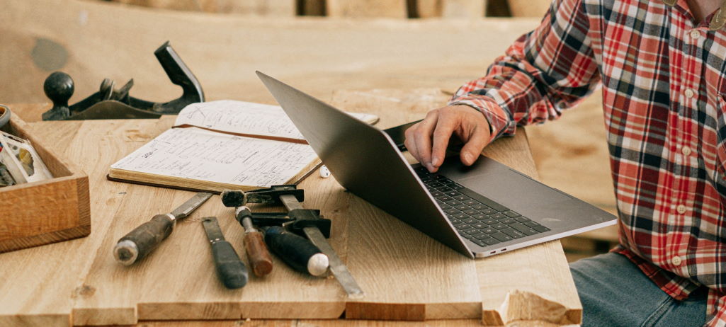 Image of a man using a laptop in a carpenter's workshop by Ivan Samkov taken from Pexels